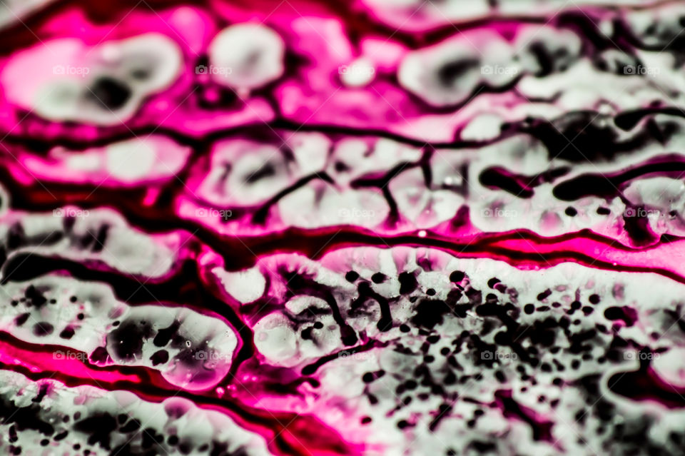 Black and pink refill ink spilled onto the white sink and the ink mixed into abstract blobs and patterns.