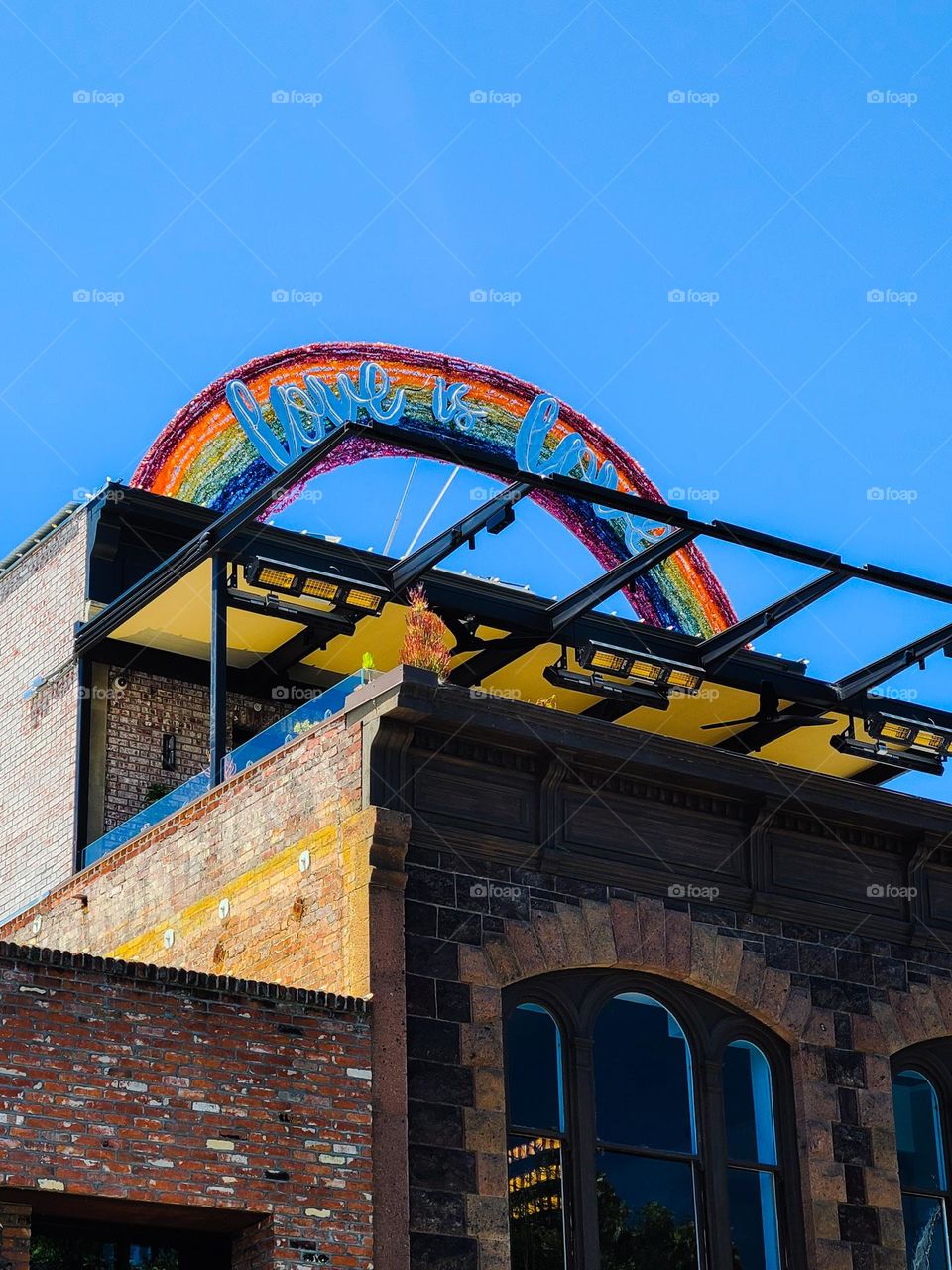 Love is Love rainbow beautifully arched above a classic brick building in downtown Napa California on a clear sunny afternoon 