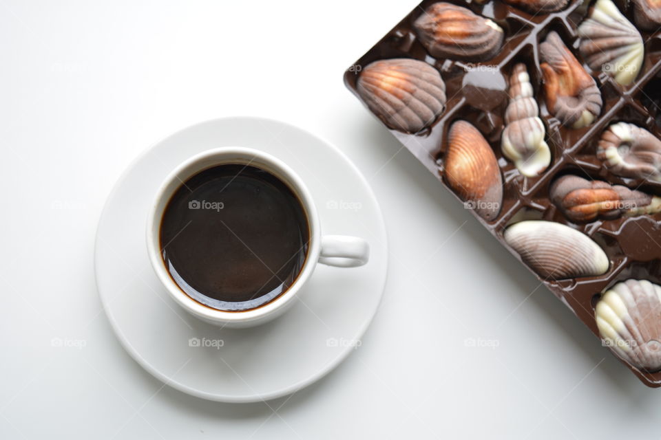 coffee cup and chocolate candies on a white background top view