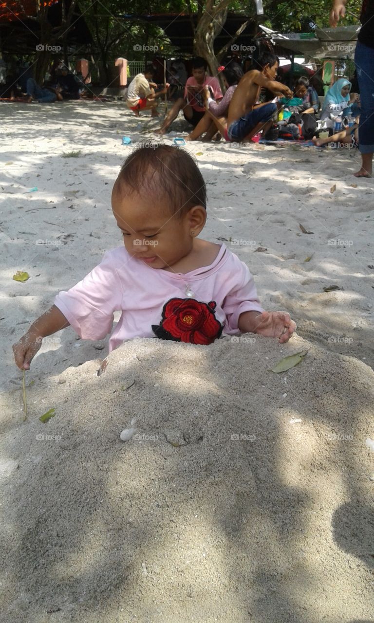 The baby cheerful in the grave in the sand shore