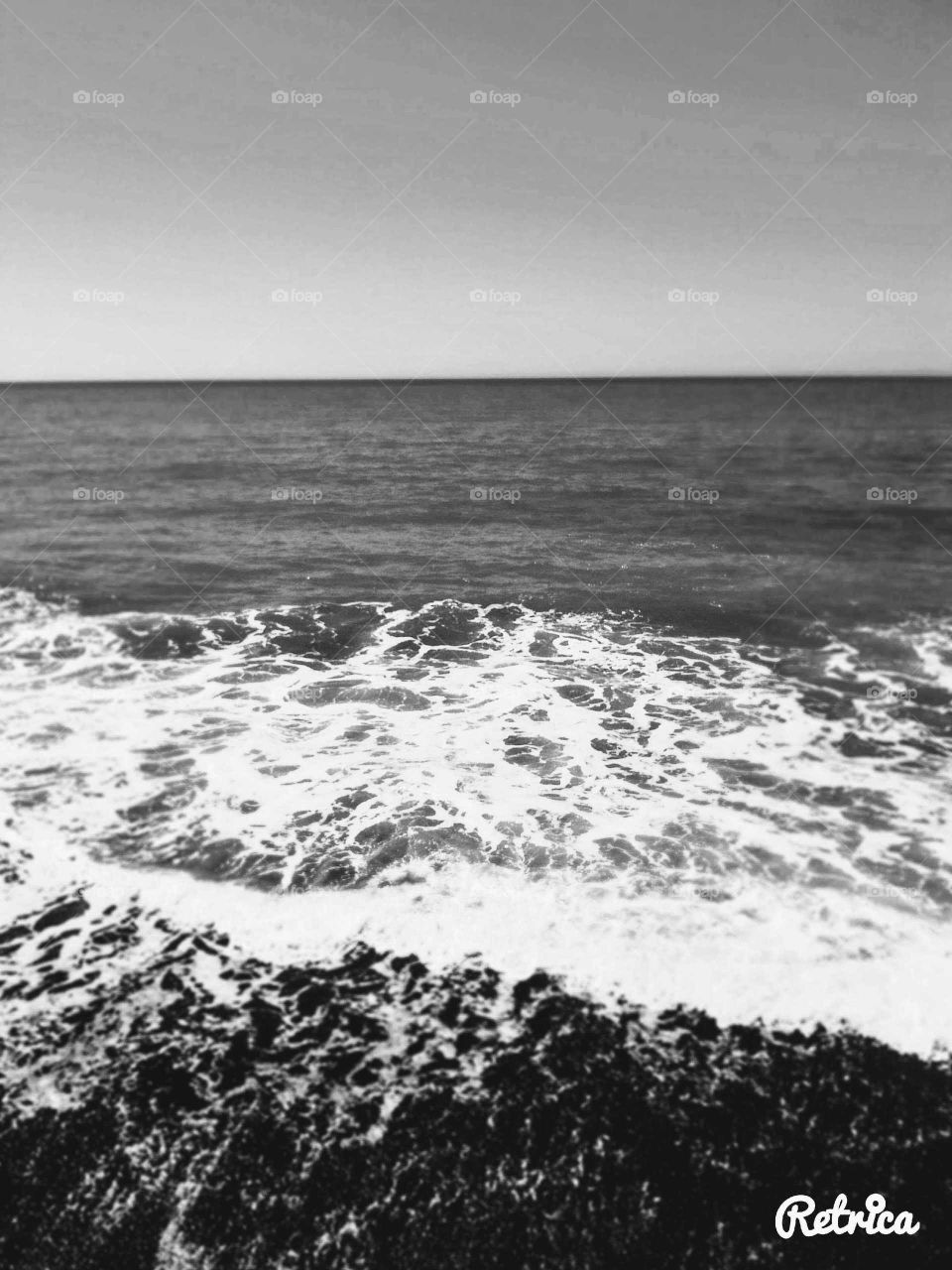 Black and white beach scene small waves on a calm summers day.