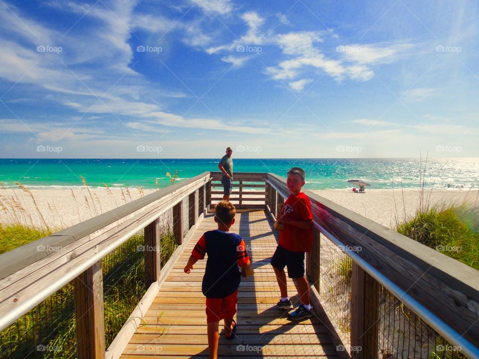 Father and sons on boardwalk at beach