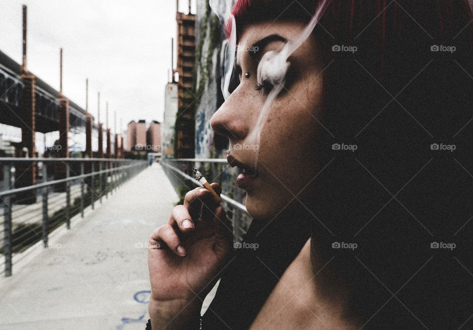 urban portrait of a tattoed pretty girl smoking cigarette