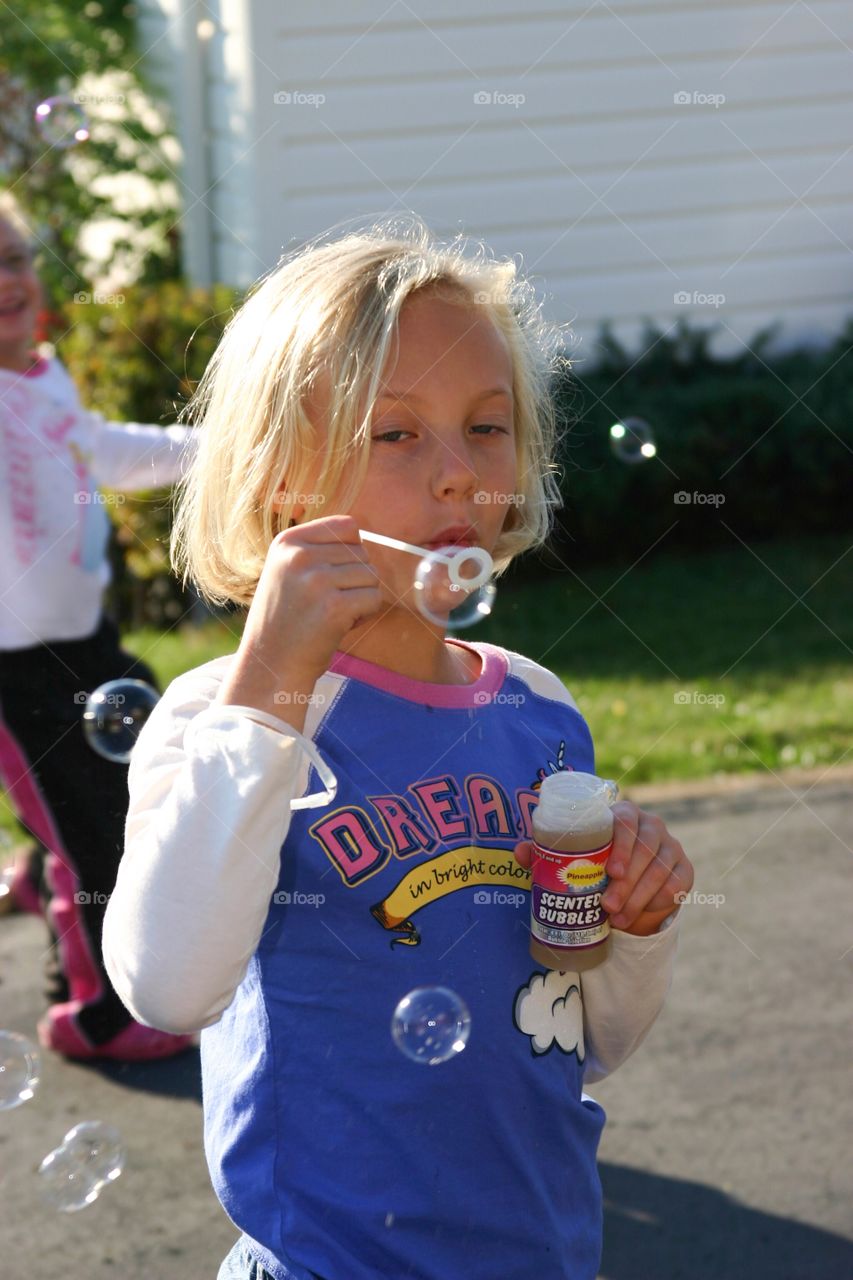 Little girl blows bubbles 