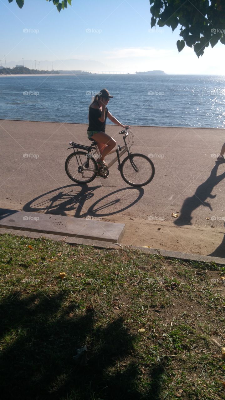 mulher pedalando no calçadão da praia