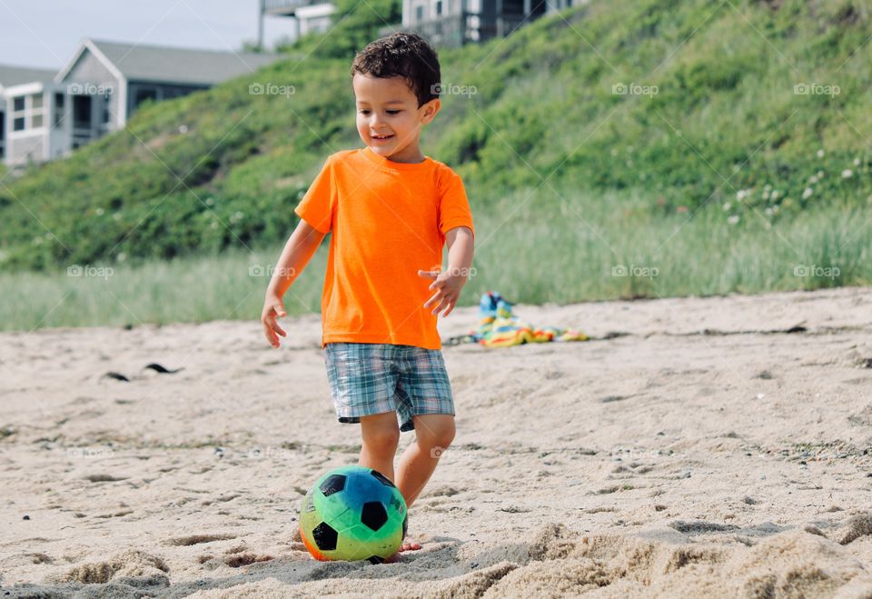 Child playing soccer on the beach