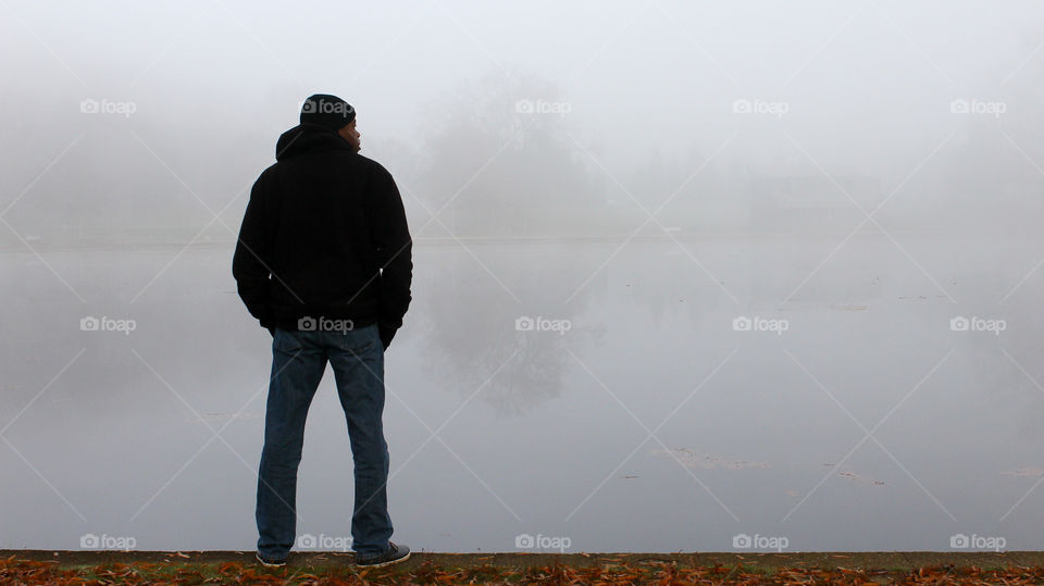 Man standing at the Water's Edge on a Foggy Morning