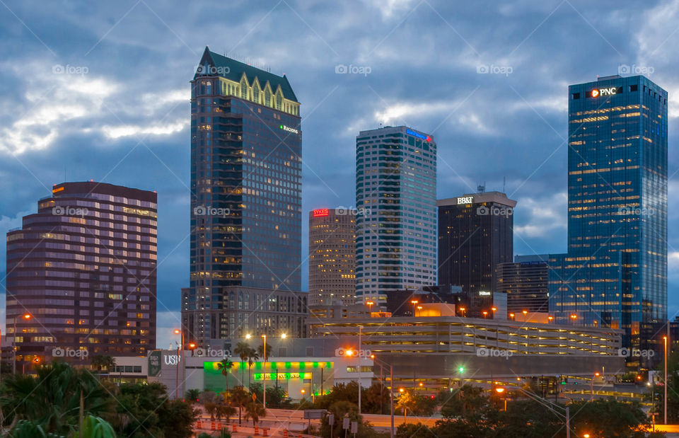 downtown city skyline at blue hour with colorful city lights and thick blue clouds in the sky