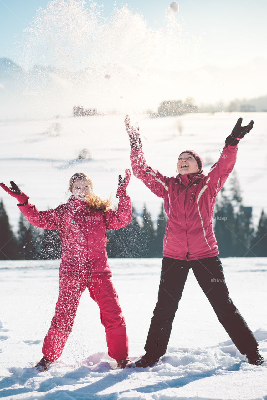 Mother enjoying the snow with her daughter outdoors in the wintertime