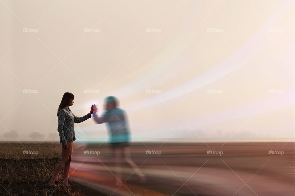 A girl touches her reflection through a moving wall of light