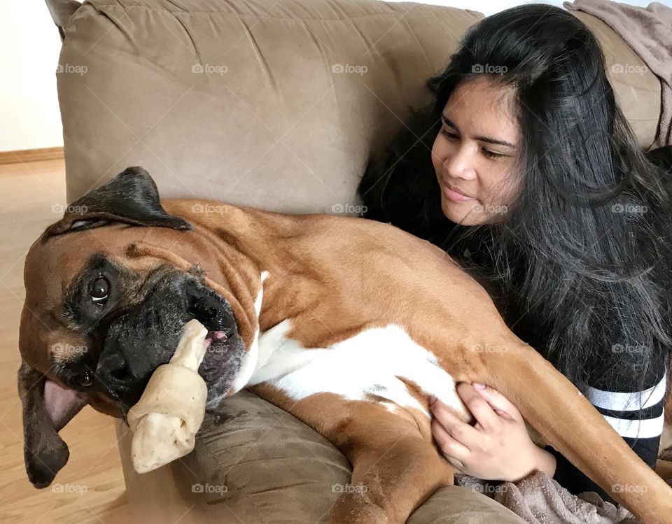 Girl with her boxer as he chews a bone