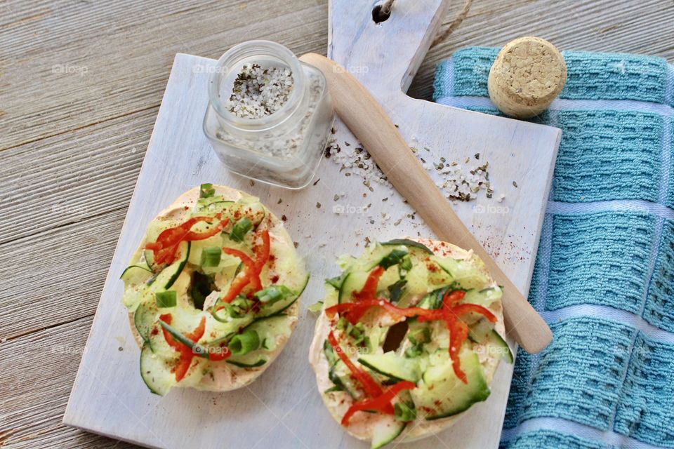 Salmon spread with thinly sliced cucumber, red pepper, and green onion on a toasted bagel 🥯