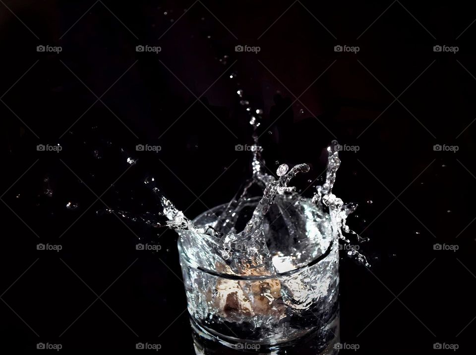 low key splash picture close up from a glass with clear water splashing out