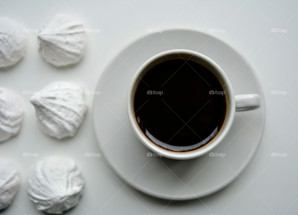 coffee mug and sweet sugar meringues on a white background top view