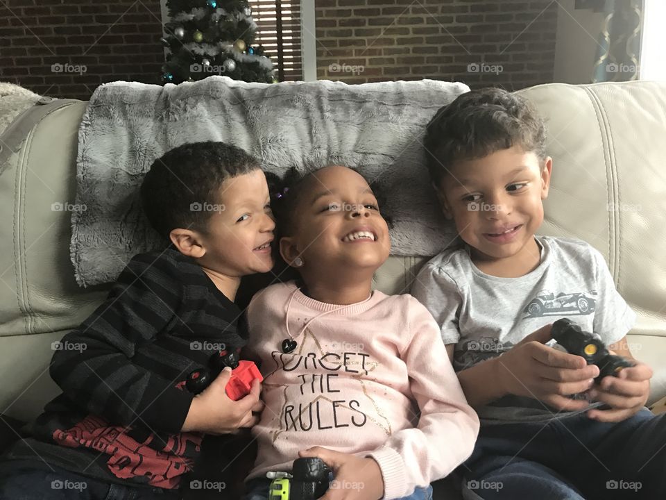 Three kids laughing on a couch