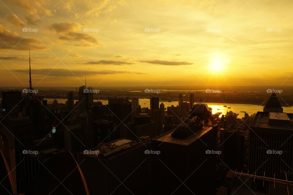 silhouette of buildings and yellow reflection of the sun on water