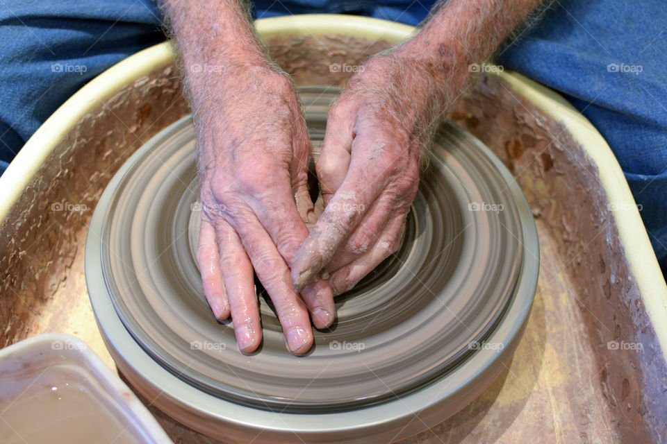 A craftsman making a clay pot with a pottery wheel. 