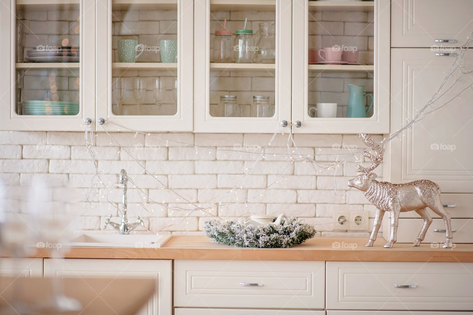 Festive winter cozy kitchen interior with garlands, decorations and gifts.  Christmas dinner at the decorated table.