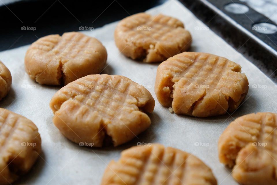 Close up of raw American peanut butter cookies on a baking sheet lined with baking paper laying on a checkered napkin