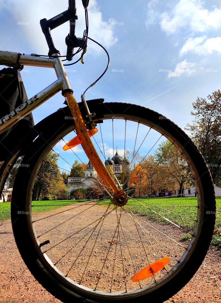 Bicycles. Through the front wheel of the bike you can see the path, autumn trees and the domes of the temple