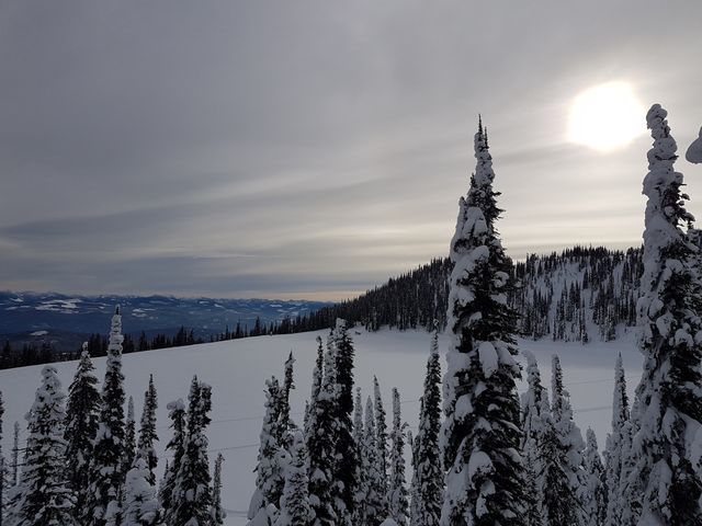 Sun behind the clouds over a lake on the side of a mountain, Big White, Canada