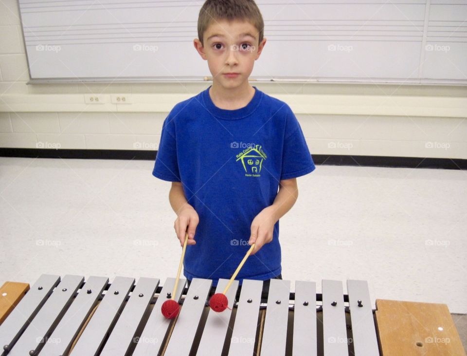 Young boy learning xylophone. 