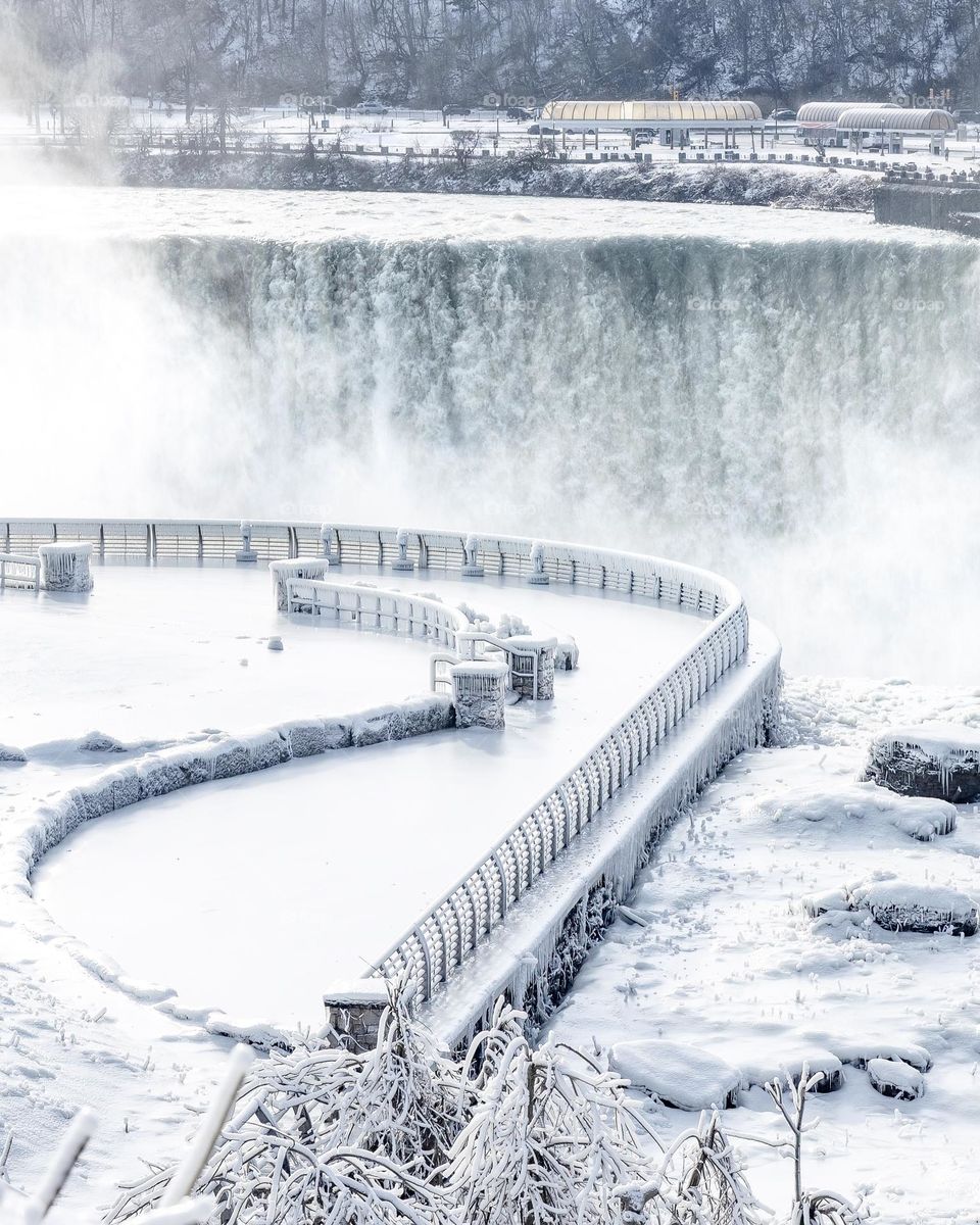 Viewing platform covered in snow and ice overlooking a massive waterfall