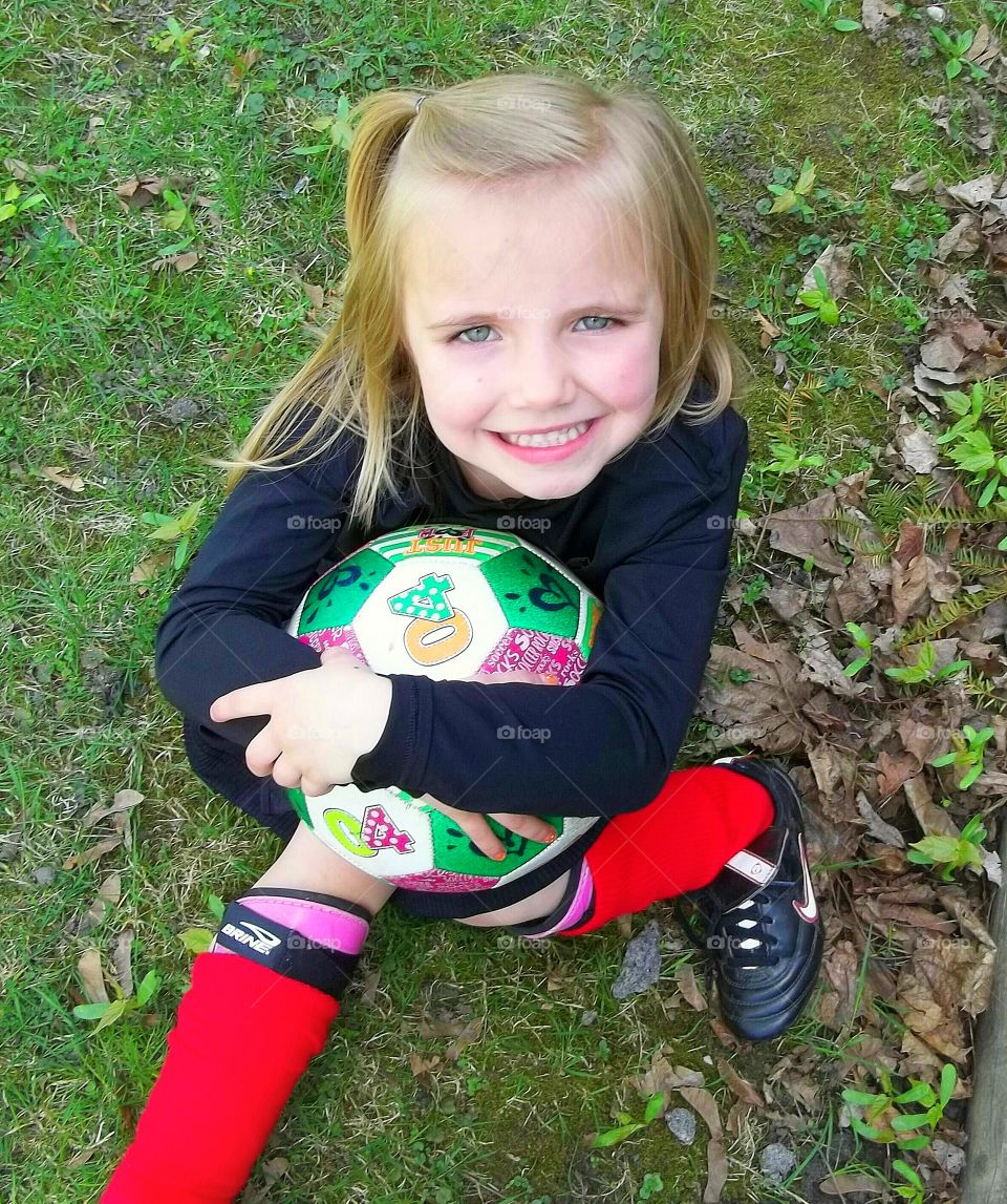 Cute girl sitting in park with ball