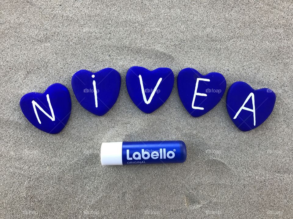 Nivea label product with blue colored heart stones with sand background