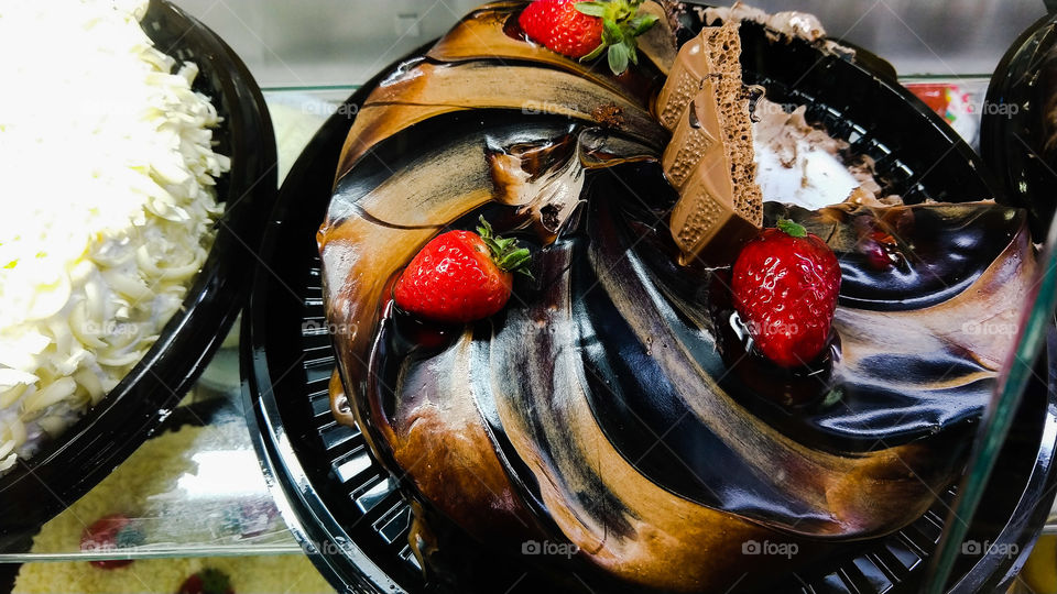 Confeitaria, bolo delicioso com recheios doces e coberturas de chocolate escuro e morangos.