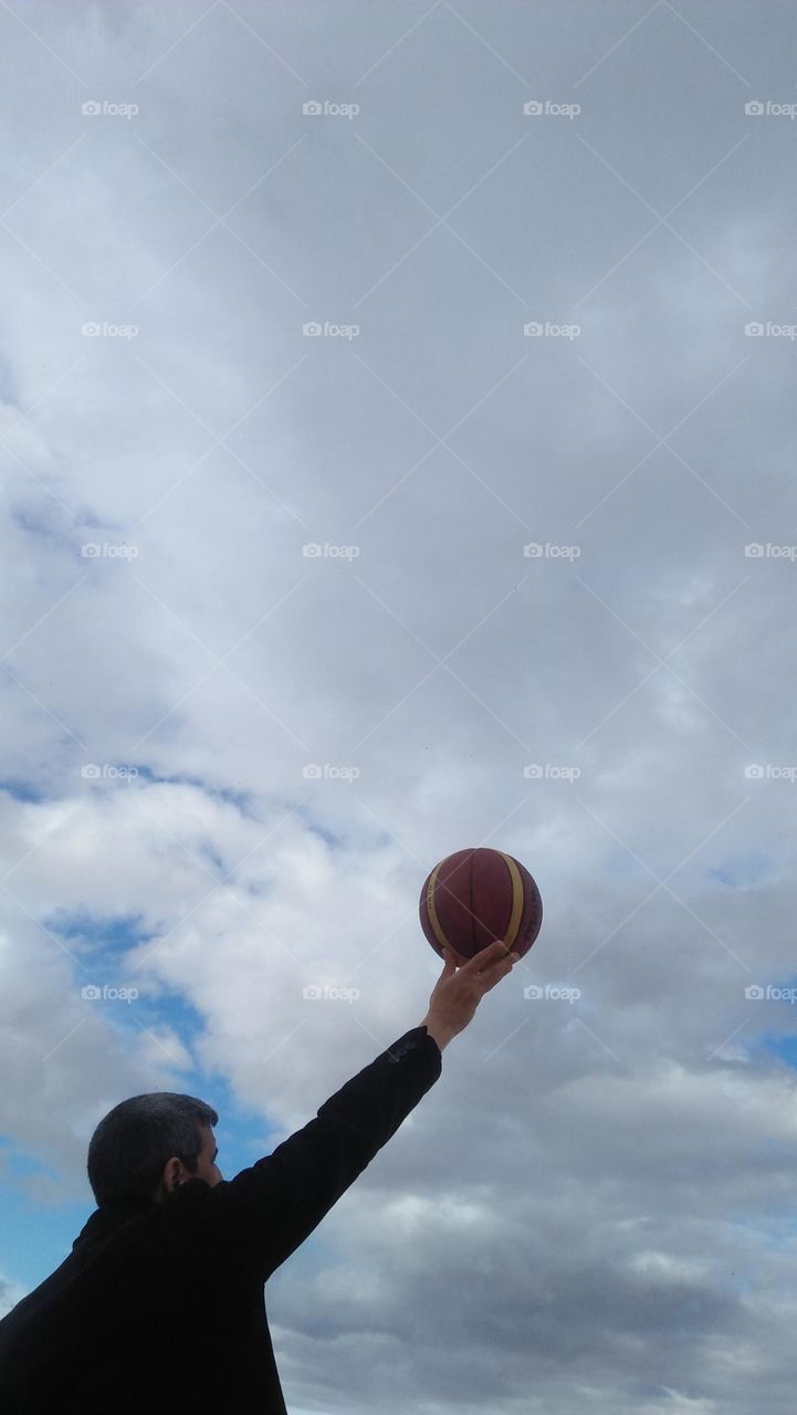  l hold  a basketball high to hug the sky.