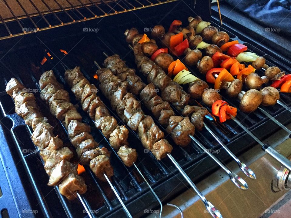 Shish kabob skewers of meat and vegetables cooking on the grill