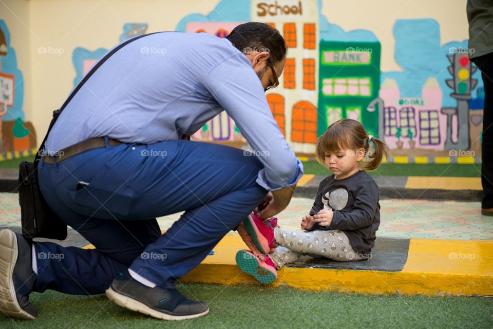 dad tying his daughter's shoes