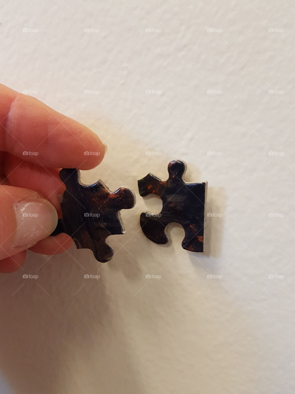 Close-up of puzzle pieces with human finger