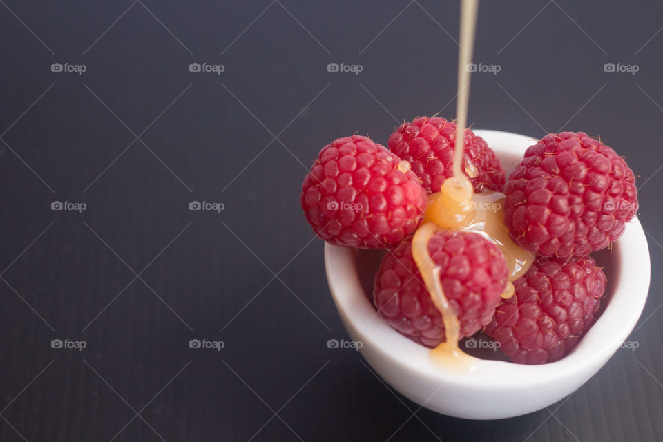 Raspberries with caramel sauce. Raspberries in a bowl being drizzled with caramel sauce