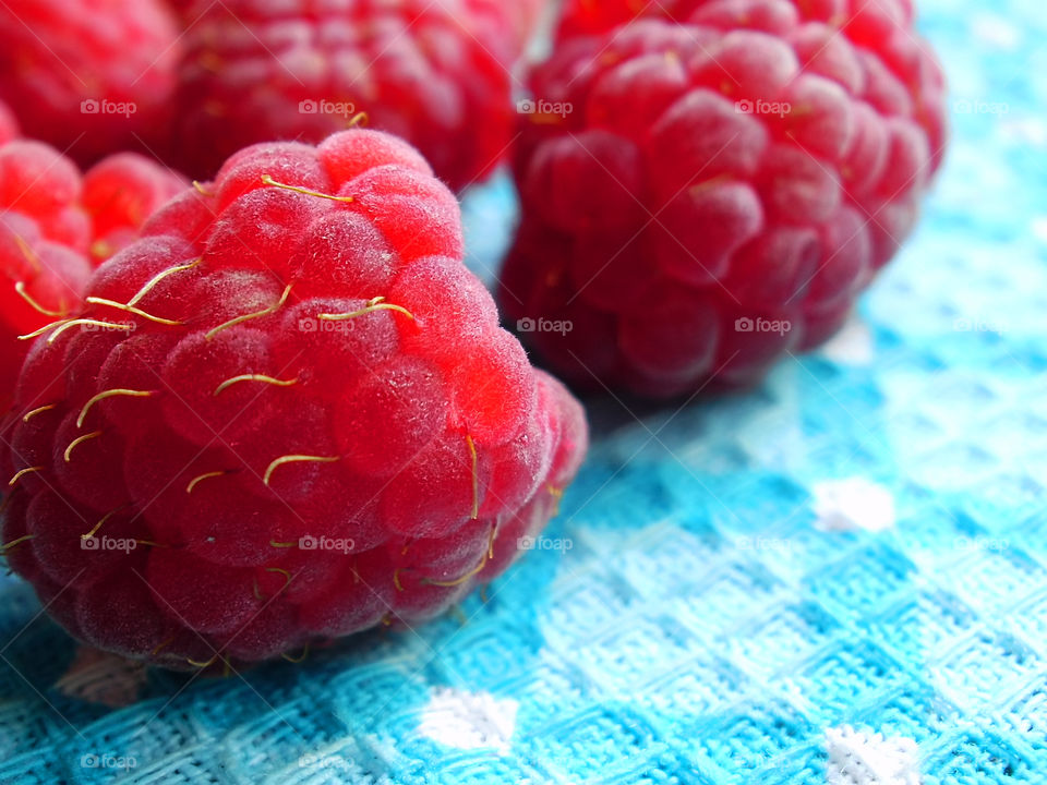 Red fresh ripe raspberries on blue textile background 