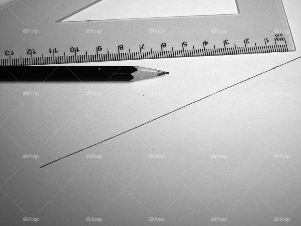 There is a pencil and a ruler on a sheet of paper.  A line is drawn on the paper.