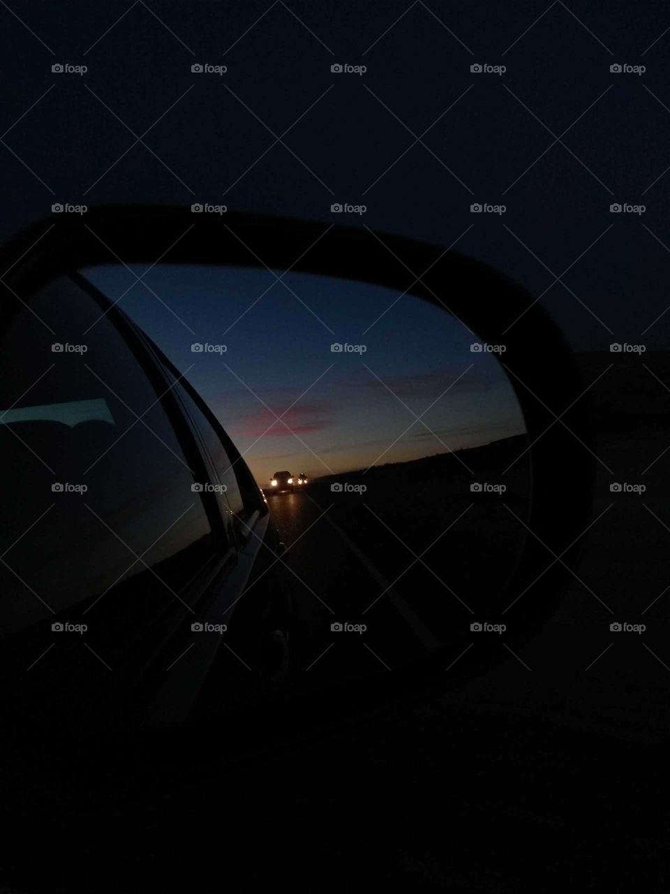 Atardecer desde la vista del espejo retrovisor de un auto durante un viaje en ruta