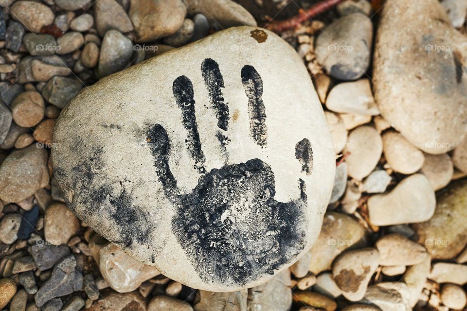 Hand print on stone. Human imprint. Close up of handmark. Sign left by human. Black print. Identity concept