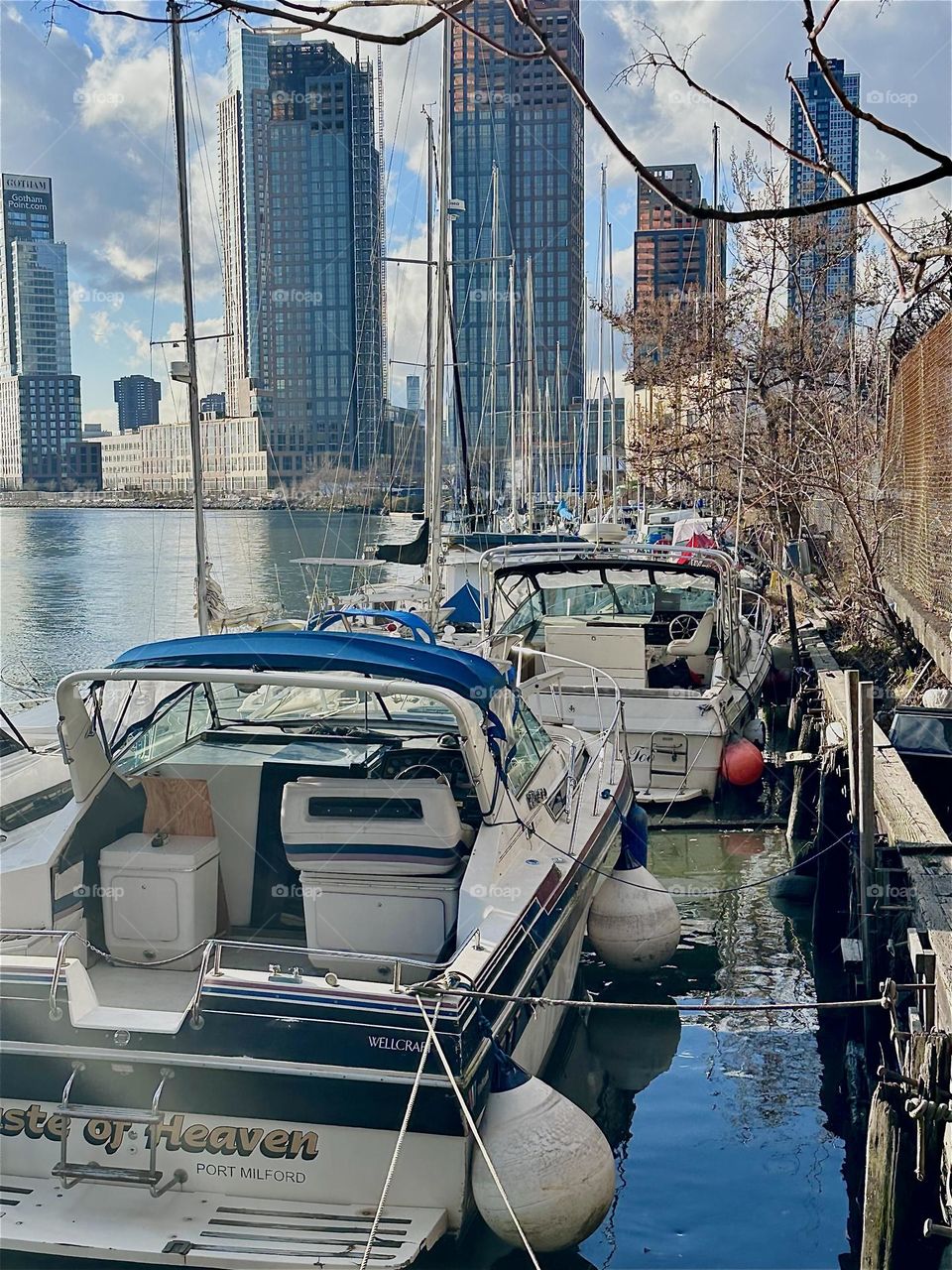These picturesque boats are tied to the shore at “Newtown Creek” by the “Pulaski Bridge” in LIC, Queens. Straight ahead across the water we see recently built high rises in LIC and in the distance “Manhattan”. 2023. Hypnotic Productions