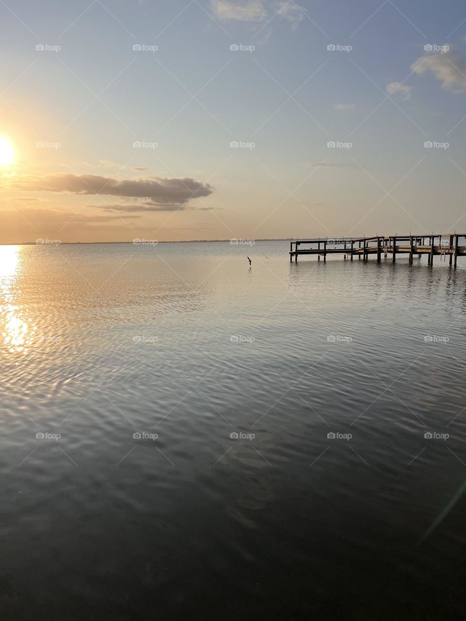 The natural ripples in the water holds the sunset reflections and balanced with the pier.