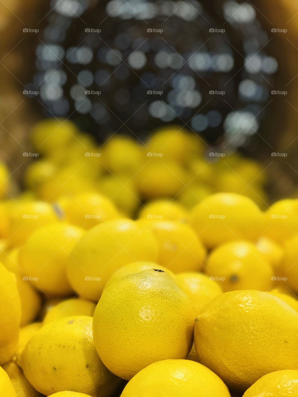 Fresh yellow lemons in the flatten babmboo basket.