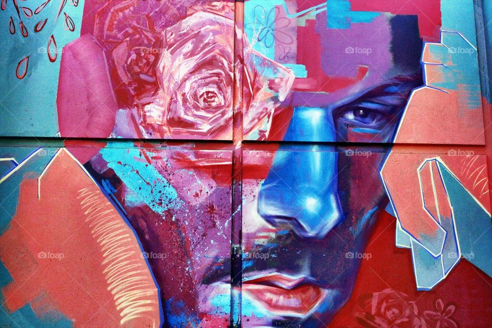 looking at the vibrant colors on the side of a building of a graffiti artist artwork