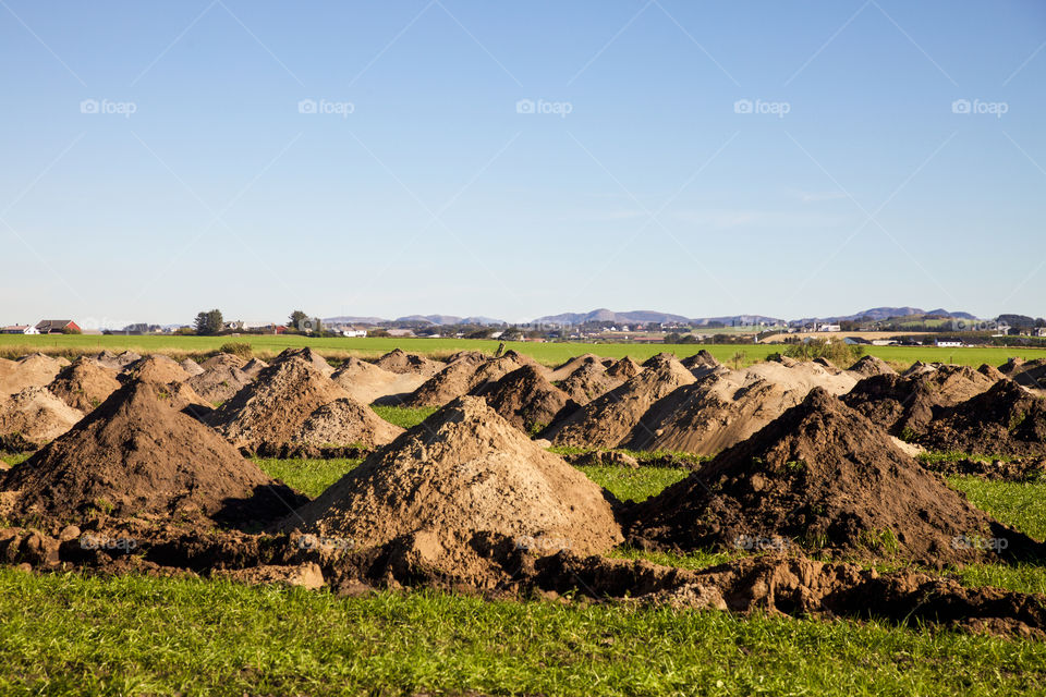 Soil heap on the grassy land against clear sky