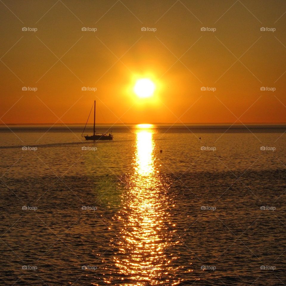 Reflection of sunlight and sailboat at sea