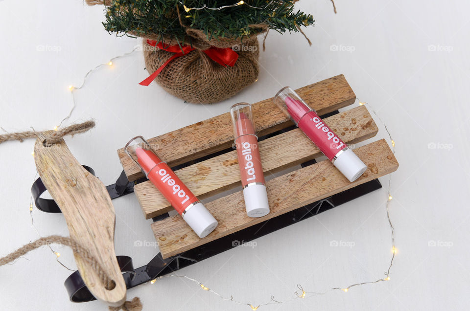 Row of Labello lip crayons on a mini wooden sled next to a pine tree