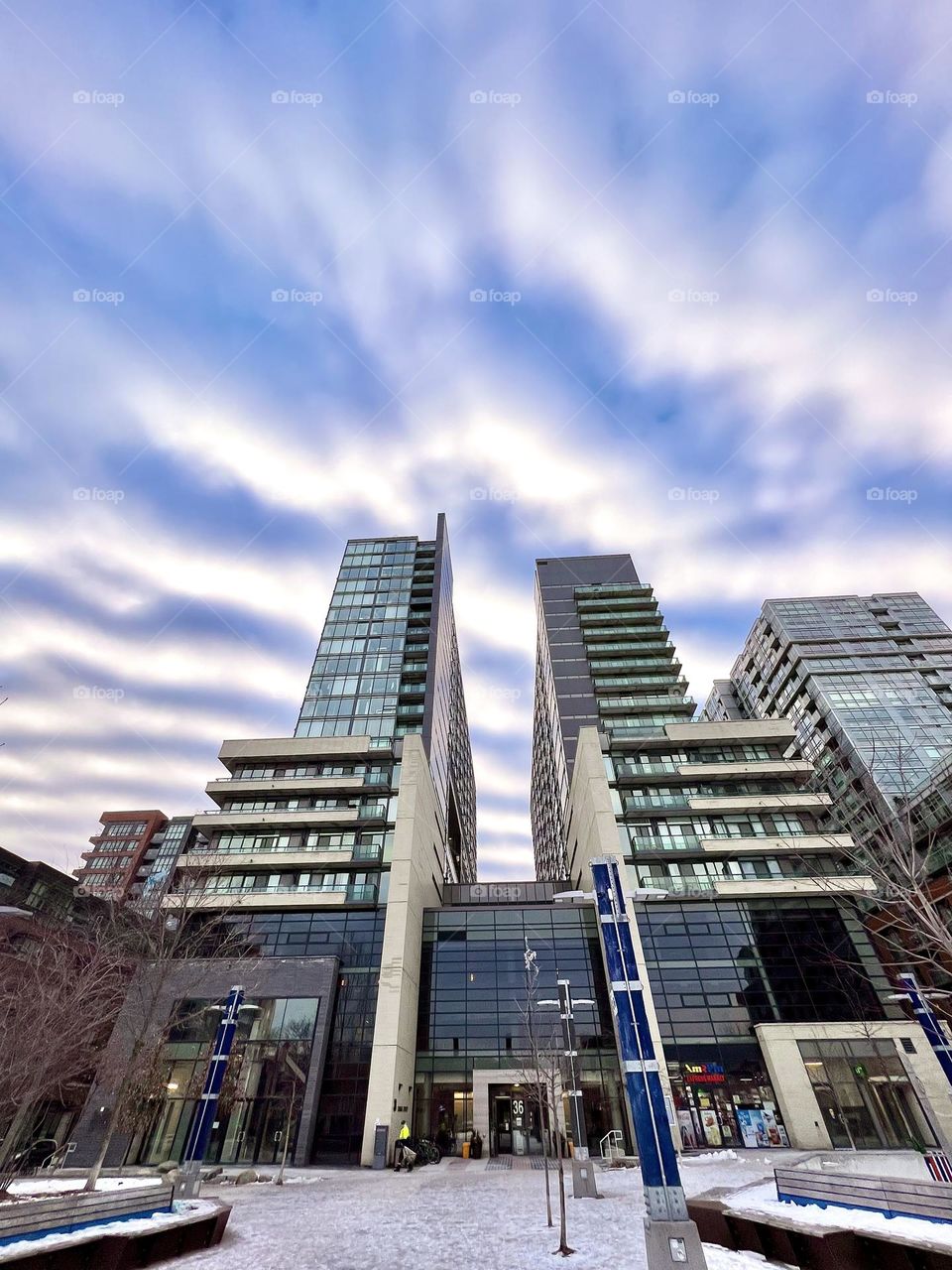 Tall apartment building towers stretching into the sky with high level fluffy clouds. (iPhone 13)