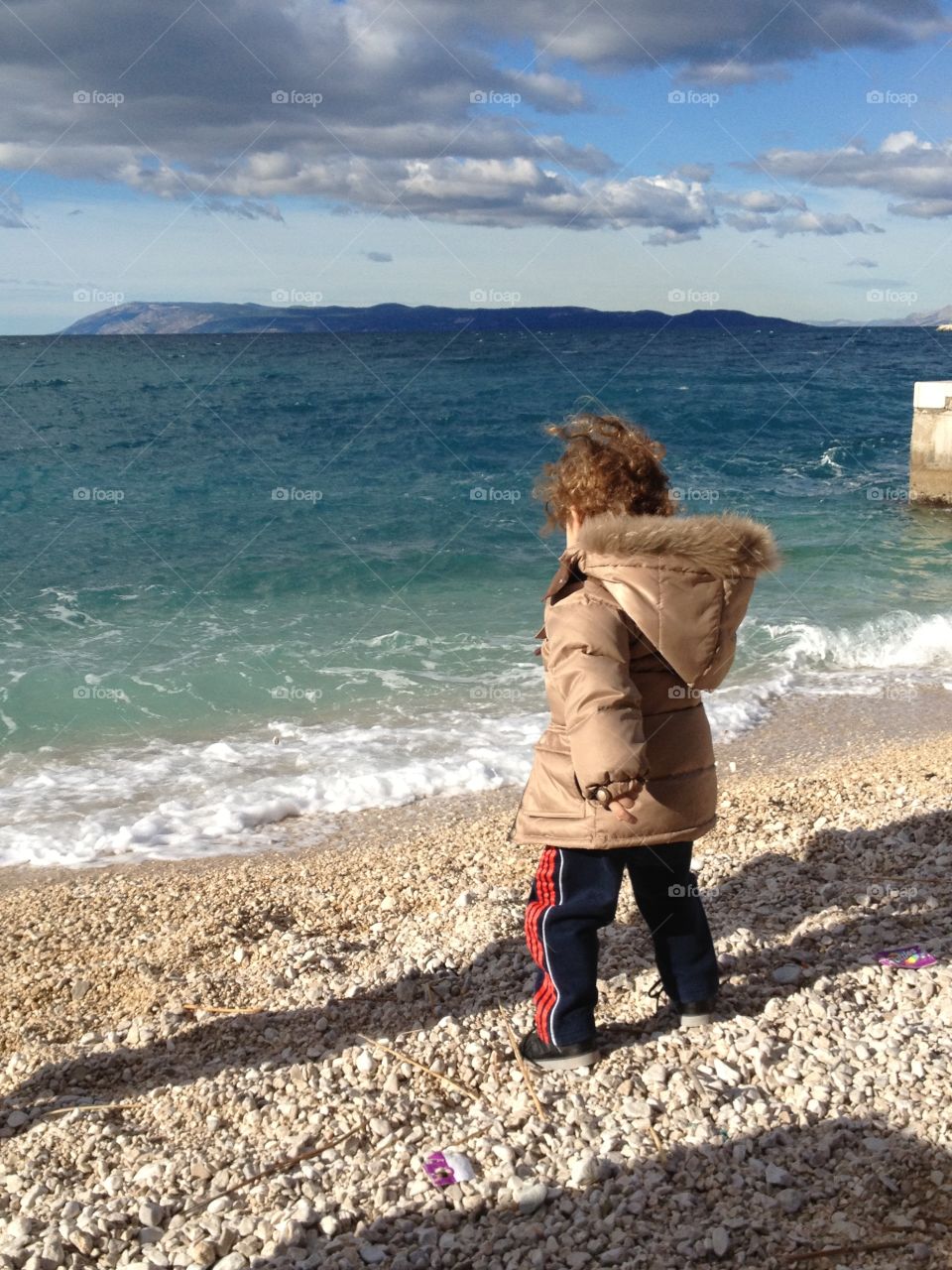 Sea and kid. Boy throws stones in the sea