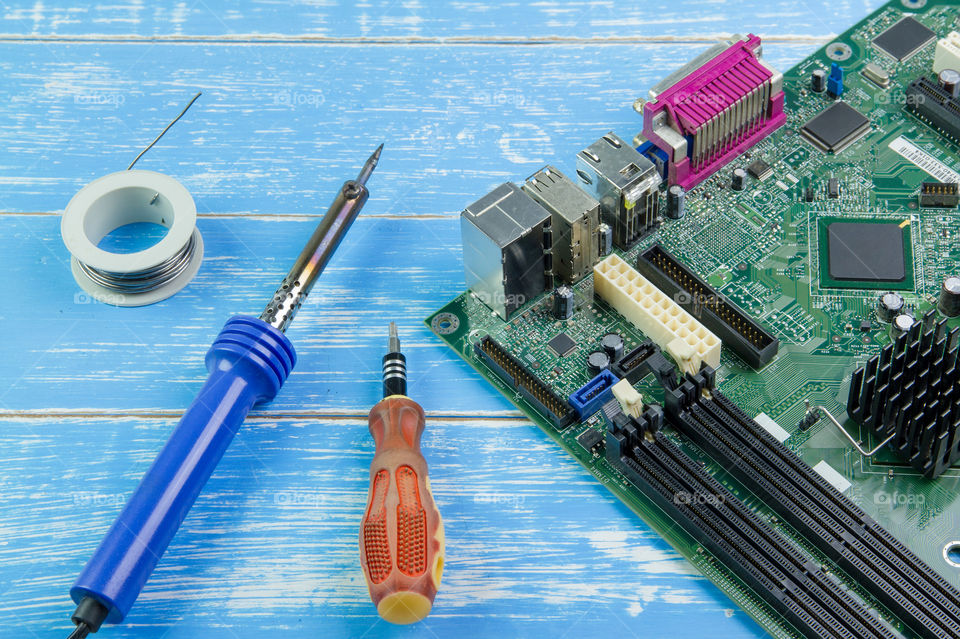 Computer motherboard and equipment repair on the blue wooden background.