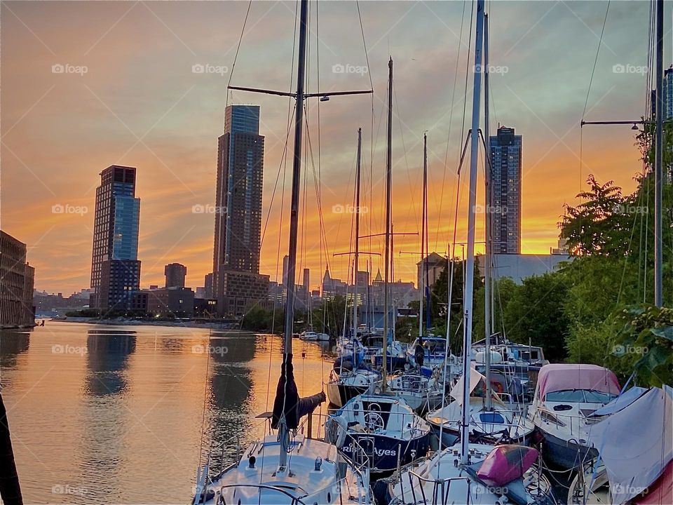 Evening impressions during a intense and very fiery sunset over the “East River” at “Newtown Creek” by the “Pulaski Bridge”. The clouds in the sky are leaving silvery streaks. 2022. Hypnotic Productions